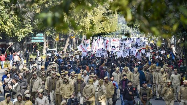 Police personnel walk in front of JNU students' protest march from Mandi House to HRD Ministry, demanding removal of the university vice-chancellor, at Ferozeshah Road in New Delhi, Thursday, January 9, 2020.(PTI Photo)