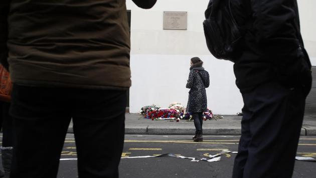 A woman pays tribute in front of a wreath of flowers, outside the satirical newspaper Charlie Hebdo’s former office, after a ceremony to mark the fifth anniversary of the attack in Paris, France. An extremist attack on Charlie Hebdo five years ago, decimated its editorial staff, killed a bystander who happened to be in the building, and left a patrol officer lying dead in the street outside. (Thibault Camus / AP) A woman pays tribute in front of a wreath of flowers, outside the satirical newspaper Charlie Hebdo’s former office, after a ceremony to mark the fifth anniversary of the attack in Paris, France. An extremist attack on Charlie Hebdo five years ago, decimated its editorial staff, killed a bystander who happened to be in the building, and left a patrol officer lying dead in the street outside. (Thibault Camus / AP)