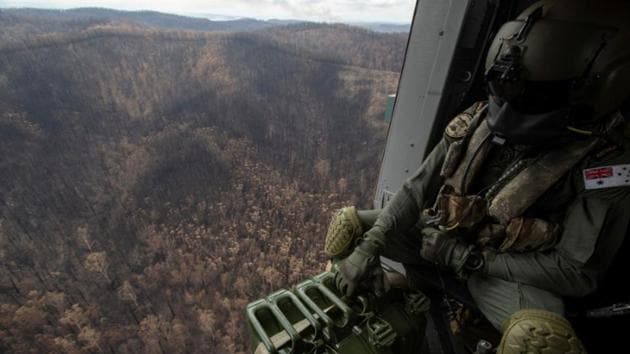 A Royal Australian Navy aircrewman flies over the burnt countryside of New South Wales, Australia, inside an MRH-90 helicopter during Operation Bushfire Assist 2020. (Photo: Reuters) A Royal Australian Navy aircrewman flies over the burnt countryside of New South Wales, Australia, inside an MRH-90 helicopter during Operation Bushfire Assist 2020. (Photo: Reuters)