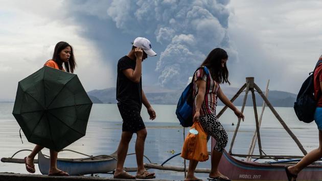 Residents walk past wooden boats as Taal volcano erupts in Tanauan town, Batangas province, south of Manila, Philippines. Clouds of ash blew far north of the Philippines’ Taal volcano, reaching Manila, the country’s bustling capital, and forcing the shutdown of its main airport after lava gushed out of the mountain on Monday. Thousands of villagers were fleeing to safety, but officials say the number could swell to hundreds of thousands. (Ted Aljibe/AFP) Residents walk past wooden boats as Taal volcano erupts in Tanauan town, Batangas province, south of Manila, Philippines. Clouds of ash blew far north of the Philippines’ Taal volcano, reaching Manila, the country’s bustling capital, and forcing the shutdown of its main airport after lava gushed out of the mountain on Monday. Thousands of villagers were fleeing to safety, but officials say the number could swell to hundreds of thousands. (Ted Aljibe/AFP)