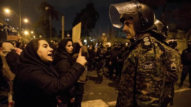 A woman attending a candle-light vigil to remember the victims of the Ukraine plane crash, speaks to a policeman asking for his sympathy, at the gate of Amri Kabir University in Tehran. (Mona Hoobehfekr/AP)