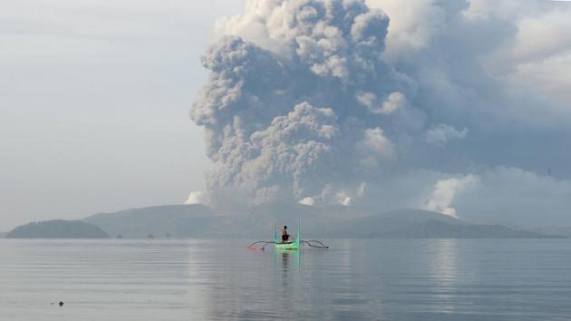 A youth living at the foot of Taal volcano rides an outrigger canoe while the volcano spews ash as seen from Tanauan town in Batangas. The government volcano-monitoring agency raised the danger level around Taal three notches to level 4, indicating “an imminent hazardous eruption.” (Ted Aljibe/AFP) A youth living at the foot of Taal volcano rides an outrigger canoe while the volcano spews ash as seen from Tanauan town in Batangas. The government volcano-monitoring agency raised the danger level around Taal three notches to level 4, indicating “an imminent hazardous eruption.” (Ted Aljibe/AFP)