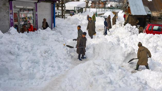Children clear snow from a road after heavy snowfall at Ferozpora village. A man also died after he fell while clearing snow from the roof of his house in south Kashmir’s Sathora Tral village on Thursday, as the valley continued to receive more snow. (S Irfan / PTI)