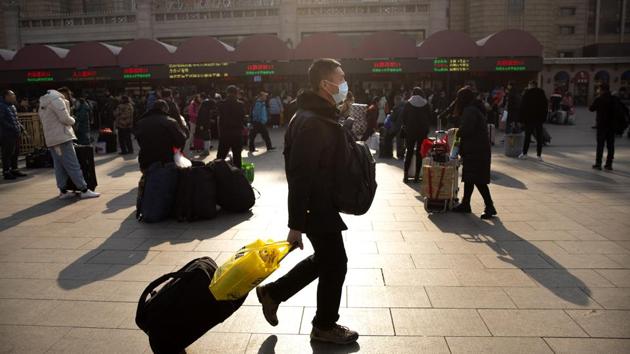 A traveller wears a facemask as he walks in front of the Beijing Railway Station on Friday.(AP Photo)