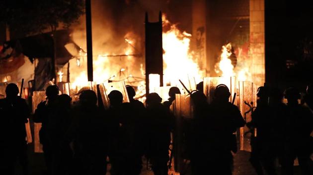 Police pass flames rising from the tents of the anti-government protesters, which were set on fire during ongoing protests against the political elite in Beirut. Lebanese anti-riot police dispersed stone-throwing protesters with tear gas in Lebanon’s capital on Sunday, as heavy rain capped a weekend of rare violence that wounded hundreds. (Hussein Malla / AP)