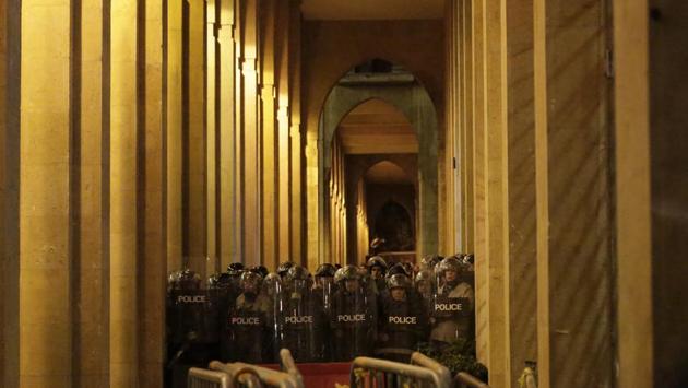 Riot police stand guard during clashes with anti-government protesters. Unprecedented protests have rocked the country since October 17, with citizens from all religious backgrounds demanding the ouster of a political class viewed as inept, corrupt and responsible for an ever-deepening economic crisis. (Hassan Ammar / AP)