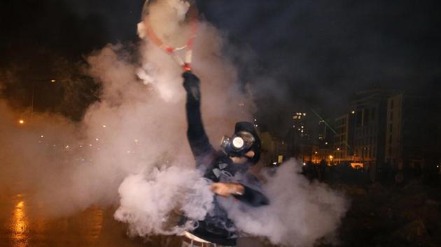 An anti-government demonstrator throws back tear gas at riot policemen with a tennis racket. Thick clouds of white tear gas billowed in central Beirut, as police pushed protesters out of a flashpoint road near parliament after hours of clashes, before the downpour largely cleared the streets. (Bilal Hussein / AP)