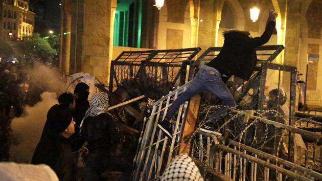 An anti-government protester stands on barriers as he throws stones against the anti- riot police. Police forces responded with water canons, rubber bullets and then thick plumes of tear gas that pushed demonstrators back towards a main square, AFP reported. (Hassan Ammar / AP)