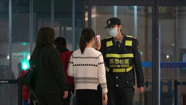 An airport staff member uses a temperature gun to check people leaving Wuhan Tianhe International Airport, January 21, 2020(AP)