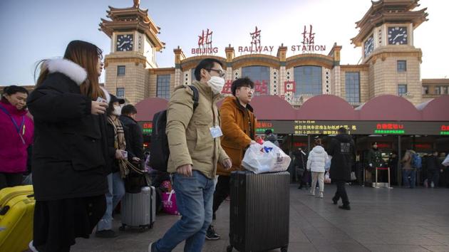 A traveller wears a face mask as he walks outside of the Beijing Railway Station in Beijing on January 20. With millions of Asians travelling on Tuesday for the Lunar New Year holiday, authorities in China confirmed that a new virus could be spread through human contact, reporting 15 medical staff had been infected and a fourth person had died. (Mark Schiefelbein / AP)