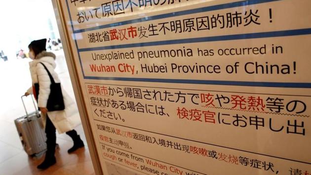 A woman wearing a mask walks past a quarantine notice about the outbreak of coronavirus in Wuhan at an arrival hall of Haneda airport in Tokyo, Japan. Internationally, (Kim Kyung-Hoon / REUTERS)
