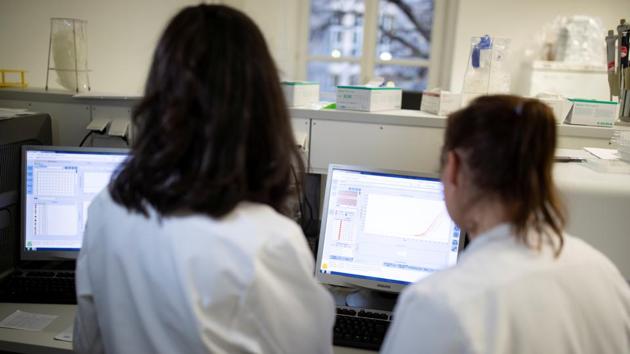 Employees of the virology department of the Charite hospital prepare a test for the new coronavirus in Berlin, Germany. (REUTERS)