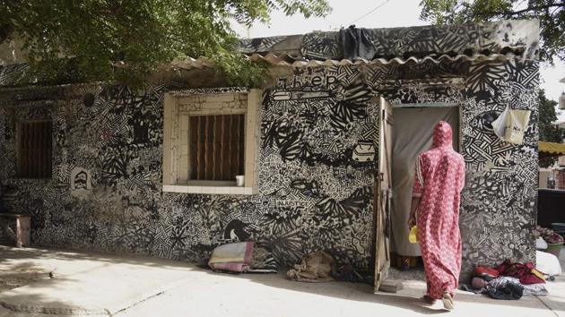 A resident enters her home with graffiti on her walls. Diallo and some associates started the association Yataal Art—which means “expand art” in the Wolof language—in 2010. They were initially asking artists to decorate walls. But now artists are coming to them, Melodie Petit, the associations’ vice-president told AFP. (Seyllou / AFP)
