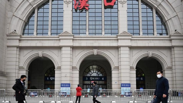 People walk past the closed Hankou Railway Station after the city was locked down following the outbreak of a new coronavirus in Wuhan, Hubei province, China.(Reuters)