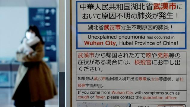 A woman wearing a mask walks past a quarantine notice about the outbreak of coronavirus in Wuhan, China, at an arrival hall of Haneda airport in Tokyo, Japan.(Reuters Photo)