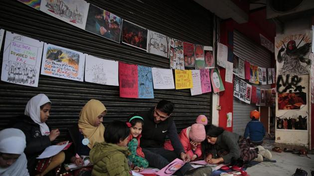 Young girls draw sketches near the protest site in New Delhi's Shaheen Bagh area, on Friday.(AP Photo)