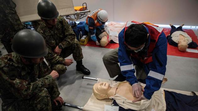 Medics perform emergency first aid as commanders bark out orders in a fevered but efficient atmosphere, sending less urgent cases to another venue. Dozens of spectators, including the walking wounded and those in wheelchairs, are evacuated through the wide boulevards of the Tokyo Bay area, but efforts are hampered by a 6.0-magnitude aftershock at 10.30am. (Behrouz Mehri / AFP)