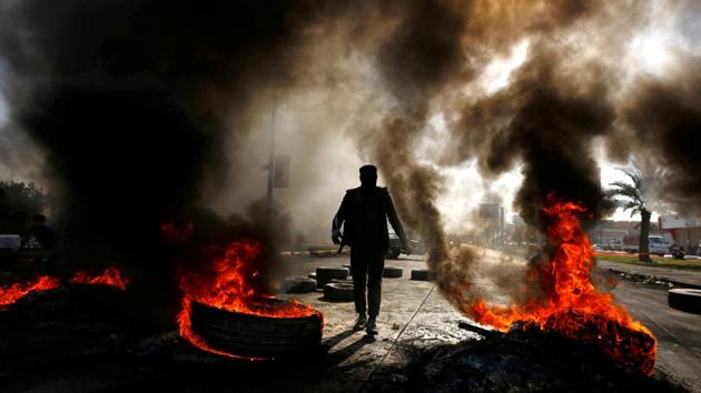A man walks between burning tires during ongoing anti-government protests in Najaf, Iraq. (Alaa al-Marjani / REUTERS) A man walks between burning tires during ongoing anti-government protests in Najaf, Iraq. (Alaa al-Marjani / REUTERS)