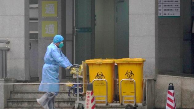 Staff moving bio-waste containers past the entrance of the Wuhan Medical Treatment Center, where some infected with a new virus are being treated, in Wuhan, China. (AP Photo) Staff moving bio-waste containers past the entrance of the Wuhan Medical Treatment Center, where some infected with a new virus are being treated, in Wuhan, China. (AP Photo)