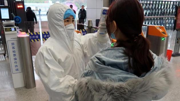 A worker in a protective suit checks a passenger arriving at the Xianning North Station on the eve of the Chinese Lunar New Year. The vast majority of cases have been in and around Wuhan or involved people who visited the city or had personal connections to those infected. Chinese officials have not yet said how long the shutdowns of the cities will last. (Martin Pollard / REUTERS)