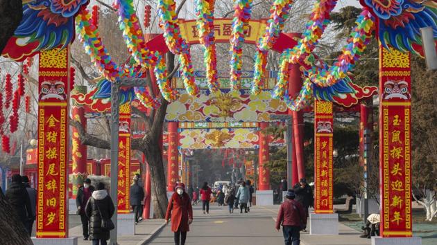 People wearing face masks walk under a canopy decorated with spinning coloured fans for a cancelled Lunar New Year temple fair at Longtan Park in Beijing. Authorities in Beijing and other cities have cancelled many public celebrations and other events marking the Lunar New Year on Saturday. (Mark Schiefelbein / AP)