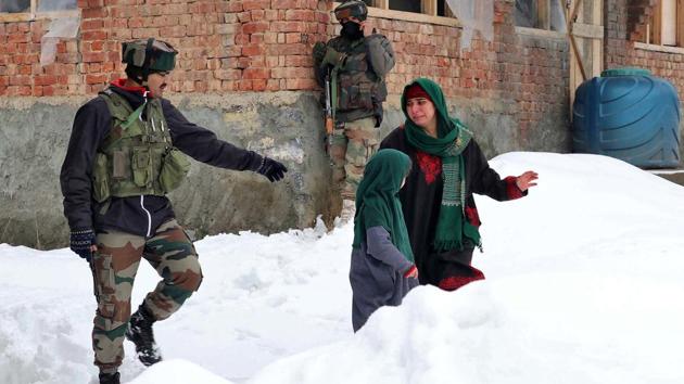 A woman walks past Indian soldiers near the site of a gun battle between suspected terrorists and security forces at Bathen village in south Kashmir's Awantipora.(Photo: Reuters)