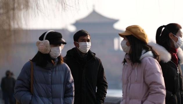 People wearing protective masks walk outside Forbidden City which is closed to visitors, according to a notice in its main entrance for the safety concern following the outbreak of a new coronavirus, in Beijing, China on January 25, 2020.(Reuters Photo)