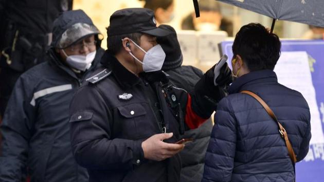 A policeman wearing a face mask takes a tourist's temperature at the Qinhuai scenic zone in Nanjing in eastern China's Jiangsu province. The virus-hit Chinese city of Wuhan, already on lockdown, has banned most vehicles downtown.(AP PHOTO.)