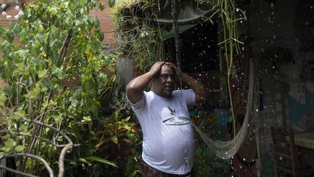 Cassiano cools off with water from his green roof. Online research for a solution led him to install the green roof -- with bromeliads, succulents and a small, flowering quaresmeira tree -- and he wants to do the same for neighbours. So far he’s had few takers, but “if God wills, people will understand that it’s necessary and urgent and it will be a job that will be really useful,” he told AP. (Silvia Izquierdo / AP) Cassiano cools off with water from his green roof. Online research for a solution led him to install the green roof -- with bromeliads, succulents and a small, flowering quaresmeira tree -- and he wants to do the same for neighbours. So far he’s had few takers, but “if God wills, people will understand that it’s necessary and urgent and it will be a job that will be really useful,” he told AP. (Silvia Izquierdo / AP)
