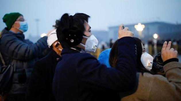 People wearing face masks use their cellphones at the Tiananmen Square, as the country is hit by an outbreak of the new coronavirus, in Beijing, China.(REUTERS)