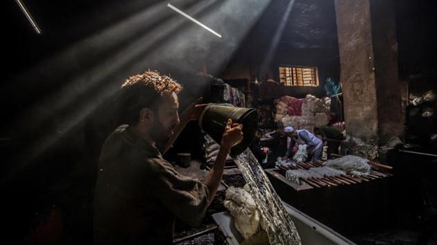 Mohamed Kamel, a 36-year-old worker pours water from a bucket to a vat as he prepares to dye yarns at Salama's workshop. Salama and his relatives lay out the long, flowing threads, which will be used for everything from handmade shoes to rugs and drapes, and dip them in huge, piping hot colour baths. (Khaled Desouki / AFP) Mohamed Kamel, a 36-year-old worker pours water from a bucket to a vat as he prepares to dye yarns at Salama's workshop. Salama and his relatives lay out the long, flowing threads, which will be used for everything from handmade shoes to rugs and drapes, and dip them in huge, piping hot colour baths. (Khaled Desouki / AFP)