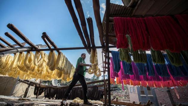 Mohamed Kamal hangs dyed yarns out to dry in the sun at the Salama workshop. Still, the legacy workshop owner is optimistic about the future of his craft. “As long as people need clothes, this job will never die,” he said with a glint in his eye. (Khaled Desouki / AFP) Mohamed Kamal hangs dyed yarns out to dry in the sun at the Salama workshop. Still, the legacy workshop owner is optimistic about the future of his craft. “As long as people need clothes, this job will never die,” he said with a glint in his eye. (Khaled Desouki / AFP)