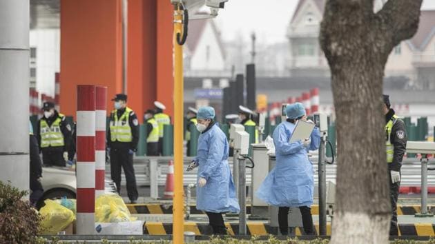 Wuhan Coronavirus: Masked health professionals and police officers stand at a screening checkpoint on a highway toll station on the outskirts of Shanghai, China.(Bloomberg)