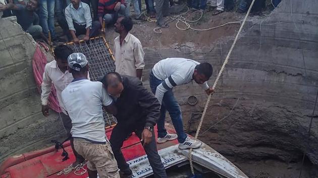 Rescue workers trying to save passengers from a bus which collided with a rickshaw and fell into a well, in Nashik.(PTI)