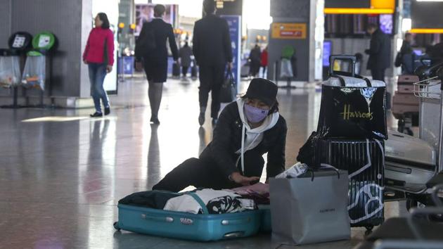 A woman wearing a face mask packs her suitcase in the departures area of Terminal 5, after it was announced British Airways has suspended all services to and from China, at London's Heathrow Airport on Wednesday.(AP Photo) A woman wearing a face mask packs her suitcase in the departures area of Terminal 5, after it was announced British Airways has suspended all services to and from China, at London's Heathrow Airport on Wednesday.(AP Photo)