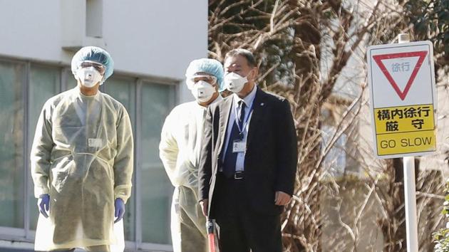 Officials wearing masks wait for the arrival of Japanese nationals evacuated from Wuhan, in Tokyo on Thursday.(Reuters Photo)