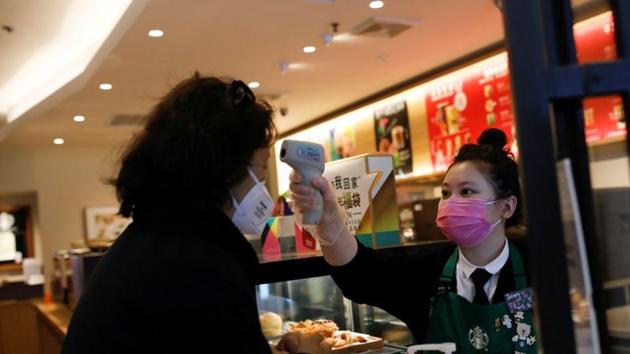A worker uses a thermometer to check the temperature of a customer as she enters a Starbucks shop as the country is hit by an outbreak of the new coronavirus, in Beijing, China.(REUTERS) A worker uses a thermometer to check the temperature of a customer as she enters a Starbucks shop as the country is hit by an outbreak of the new coronavirus, in Beijing, China.(REUTERS)