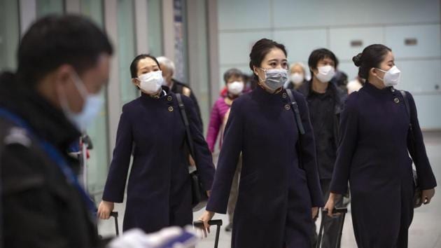 Flight crew members wearing face masks walk through the international arrivals area at Beijing Capital International Airport in Beijing.(AP Photo) Flight crew members wearing face masks walk through the international arrivals area at Beijing Capital International Airport in Beijing.(AP Photo)