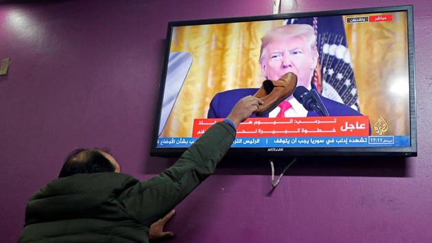 A Palestinian man places a shoe on a television screen broadcasting the announcement of Mideast peace plan by US President Donald Trump, in a coffee shop in Hebron in the Israeli-occupied West Bank. (Mussa Qawasma / REUTERS) A Palestinian man places a shoe on a television screen broadcasting the announcement of Mideast peace plan by US President Donald Trump, in a coffee shop in Hebron in the Israeli-occupied West Bank. (Mussa Qawasma / REUTERS)