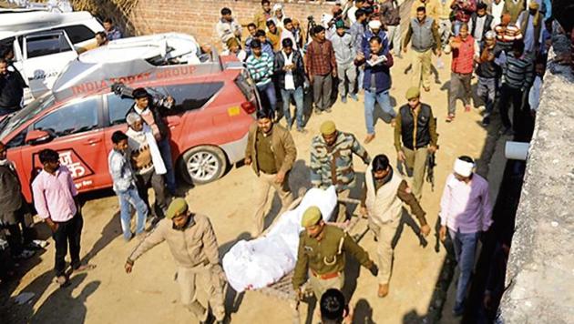 People gather as police personnel carry the body of Subhash Batham, who had taken more than 20 children hostage inside his house, after he was shot dead during a rescue operation.(Deepak Gupta/HT)