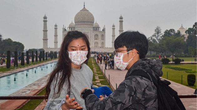 Tourists, wearing protective face masks as precautionary measures against the coronavirus, visit Taj Mahal, in Agra. (PTI)