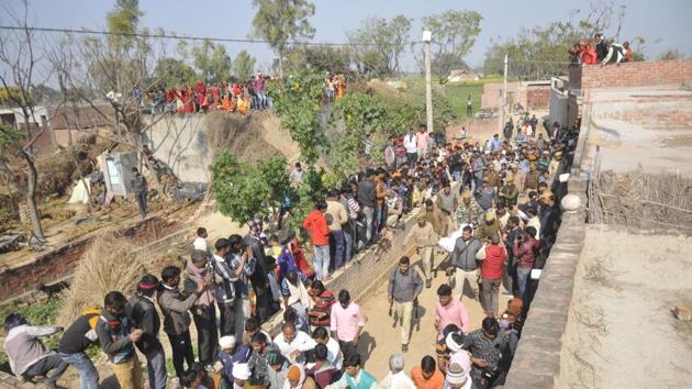 People gather as police personnel carry the corpse of Subhash Batham, who had taken more than 20 children hostage inside his house, after he was shot dead during a rescue operation, at Karthia village, Mohammadabad, in Farrukhabad district of Uttar Pradesh. (Deepak Gupta / HT Photo)