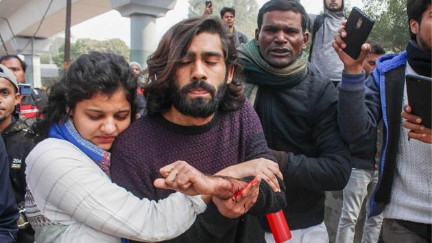 A student (C) of the Jamia Millia Islamia university, injured after an unidentified person allegedly opened fire during an anti-CAA protest, is assisted towards a hospital in New Delhi. (MD Meharban / PTI)