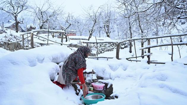 A woman washes utensils after snowfall in the outskirts of Srinagar, Jammu and Kashmir. (Tauseef Mustafa / AFP)