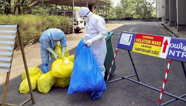 Medical staff dispose garbage outside an isolation ward for coronavirus at a hospital in Kochi.(PTI)