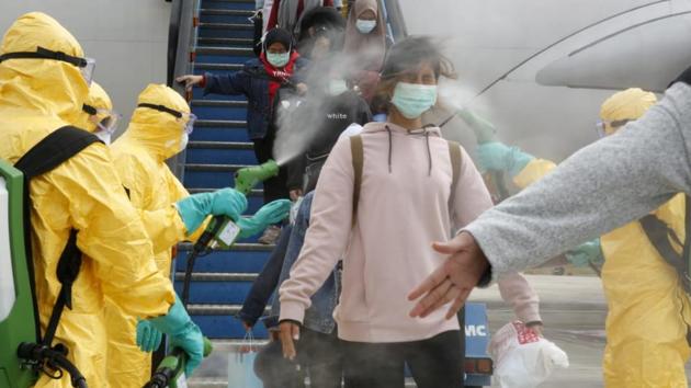 Medical officers spray Indonesian nationals with antiseptic after they arrived from Wuhan, China center of the coronavirus epidemic, before transferring them to the Natuna Islands military base to be quarantined, at Hang Nadim Airport in Batam.(REUTERS)