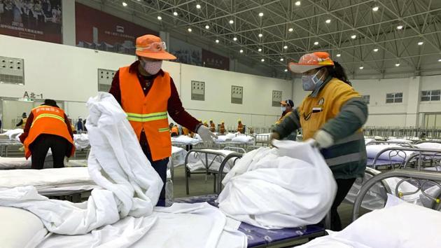 Workers arrange beds in a convention center that has been converted into a temporary hospital. The trading and manufacturing center of Wenzhou, with nearly 10 million people in coastal Zhejiang province, confined people to their homes, allowing only one family member to venture out every other day to buy necessary supplies. Huanggang, home to 7 million people, imposed similar measures on Saturday (AP)