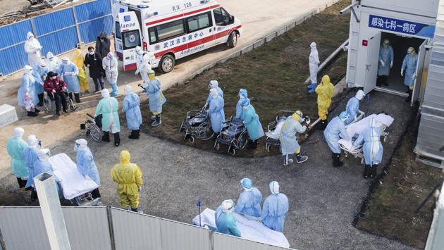 Medical workers in protective suits help transfer the first group of patients into the Huoshenshan temporary field hospital. The World Health Organization said the number of cases will keep growing because tests are pending on thousands of suspected cases. (Xiao Yijiu/Xinhua/AP)
