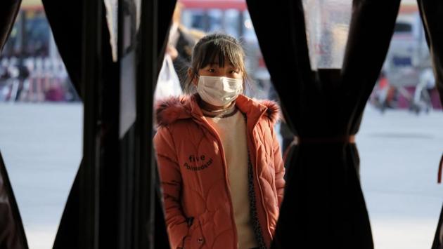 A girl wearing a face mask stands in the entrance to a shop in Wuhan. Arek is planning some kind of project with his photographs and the objects from their trip — such as their medical bracelets for travelling and ear plugs used on the military flight. His hope is that it will prompt governments to develop stronger evacuation protocols for emergency events such as that still gripping Wuhan. (Arek Rataj / AP)