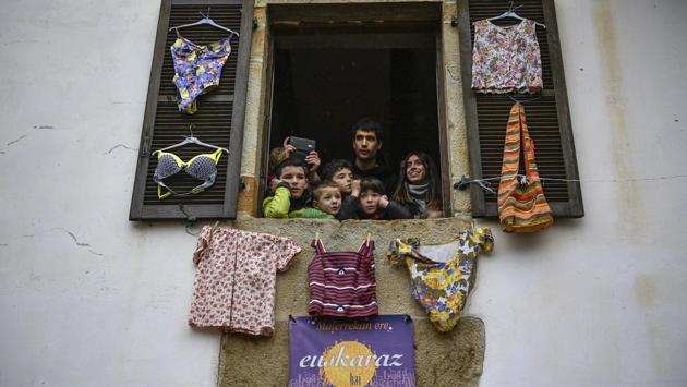 Residents look from a window as “Joaldunaks” march along the street taking part in a carnival. (Alvaro Barrientos / AP)